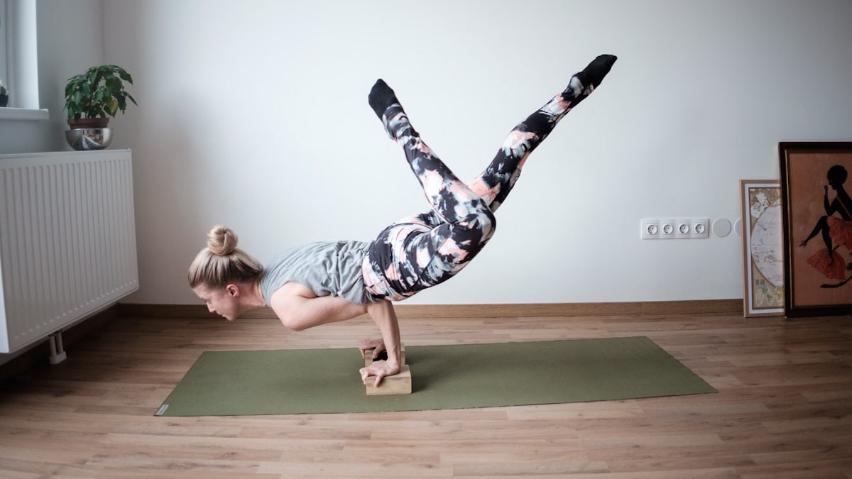 a woman doing a handstand on a yoga mat